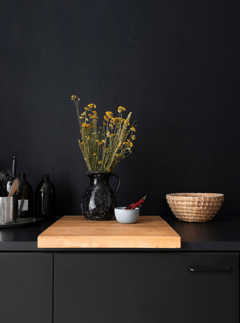 Fotografie eines Stilllebens, Blumen in einer Vase vor schwarzer Wand
